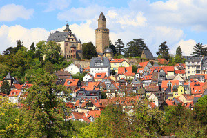 Una imagen de una ciudad llamada Königstein construida sobre una colina con una gran casa de piedra blanca en lo alto de la colina.